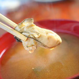 鳥羽浦村の牡蠣の写真「牡蠣の味噌汁から牡蠣の身を箸でつかむ」